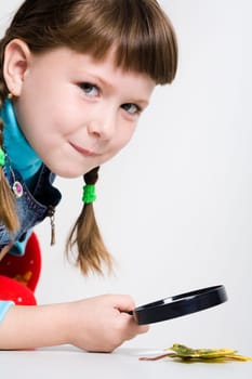 Portrait of schoolgirl with magnifying glass and autumn leaf near by