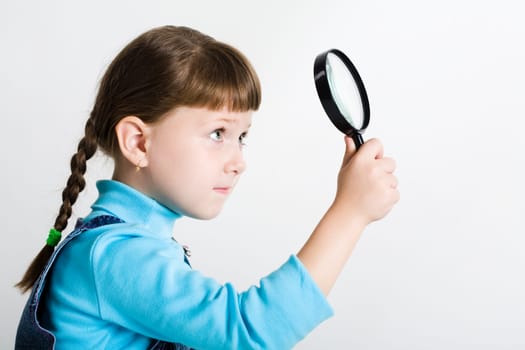 Image of cute girl with lens in hand looking slightly upwards through it