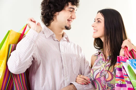 Portrait of happy couple with shopping bags looking at each other on white background