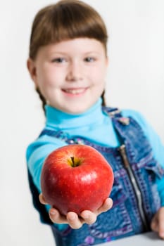 Close-up of fresh red apple in schoolgirls hand with her at background