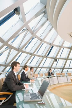 Young specialists are sitting at the round table and listening to chief of a seminar