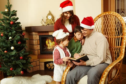 Portrait of family gathered together to read interesting fairy tale with decorated fir tree behind