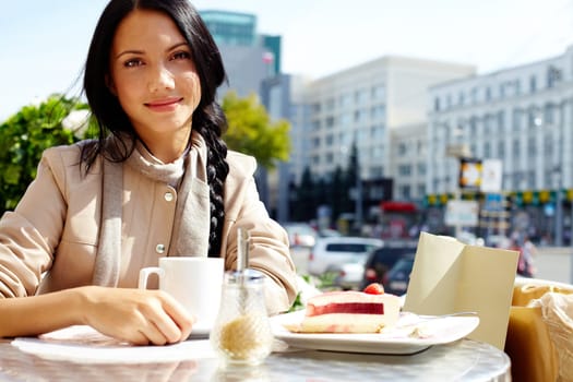 Image of happy female in open air cafe looking at camera in urban environment