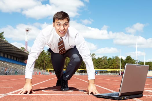 Image of handsome businessman getting ready for race at stadium
