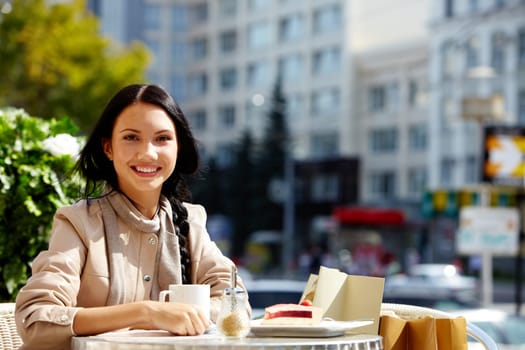 Image of happy female in open air cafe looking at camera in urban environment