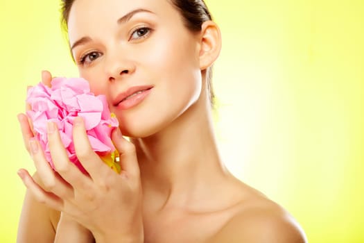 Gorgeous woman with pink flower over yellow background