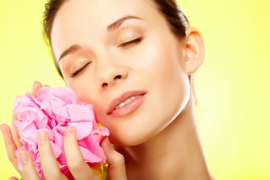 Gorgeous woman with pink flower over yellow background