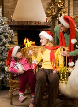 Portrait of happy parents and their cute daughter with presents at home on Chrismas day