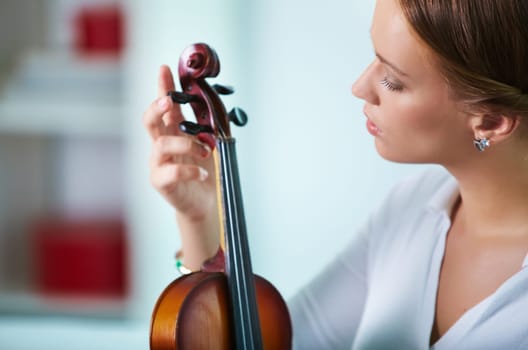 Portrait of a young female tuning the violin
