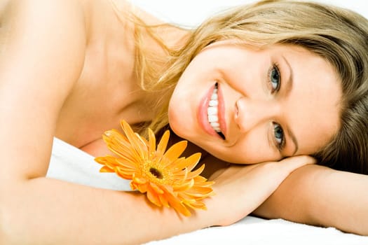 Photo of young pretty woman lying in the spa salon and enjoying aromatherapy with a flower near by