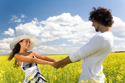 Photo of attractive couple holding by hands and whirling on the meadow at leisure