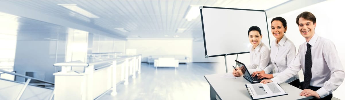 Photo of confident business team sitting at desk and looking at camera with smiles