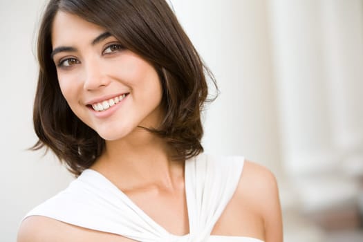 Portrait of smiling lady with brown hair on the background of columns