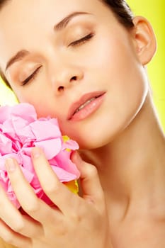 Beautiful woman with pink flower over yellow background