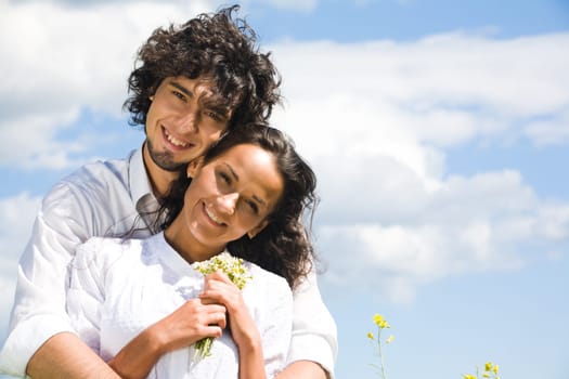 Portrait of smiling couple in white shirts on the background of sky