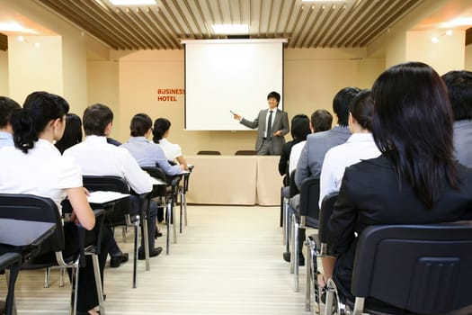 Image of confident businessman explaining something on whiteboard during conference