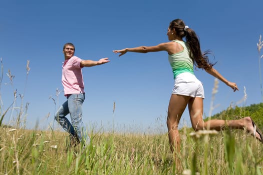 Photo of young couple running down green grass in the countryside