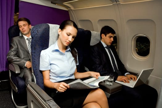 Image of pretty girl reading magazine while handsome man typing next to her