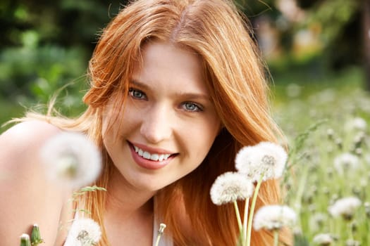 Portrait of charming girl with dandelions in green grass