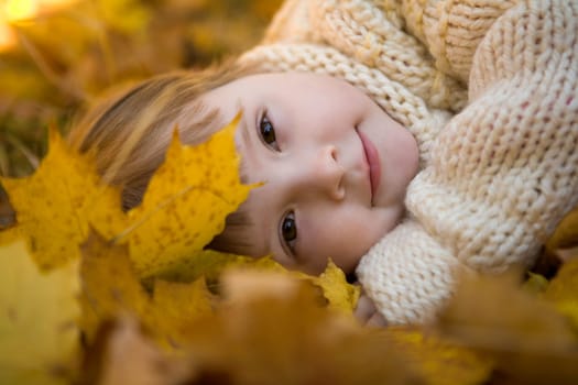 Head of girlie lying on golden leaves in autumn with peaceful expression
