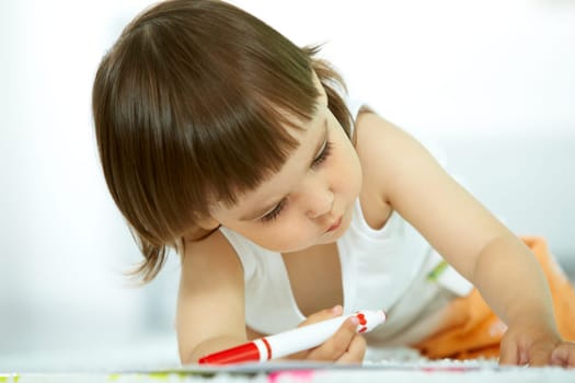 Portrait of cute girl holding highlighter and drawing
