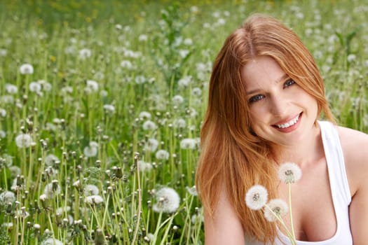 Portrait of charming girl with dandelions in green grass