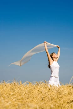 Portrait of pretty teenager holding fabric and standing in wheat field