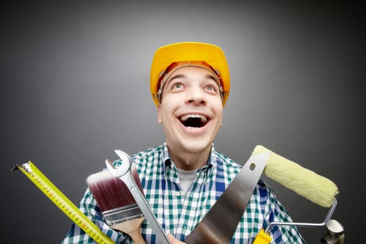 Portrait of happy craftsman with different tools in hands