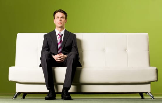 Portrait of confident boss sitting on sofa and looking at camera