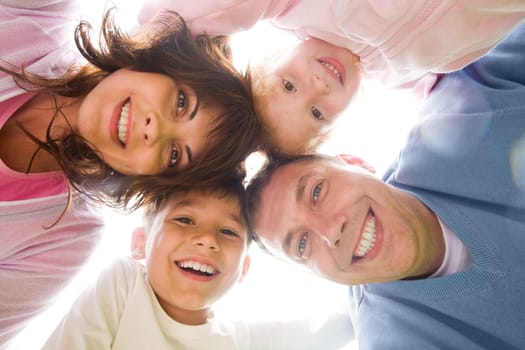 Below view of family members head by head smiling at camera