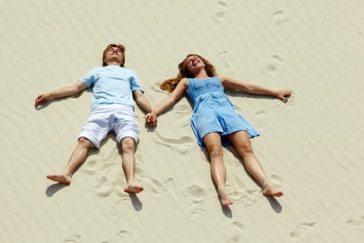 Photo of happy couple lying on sand during summer vacation