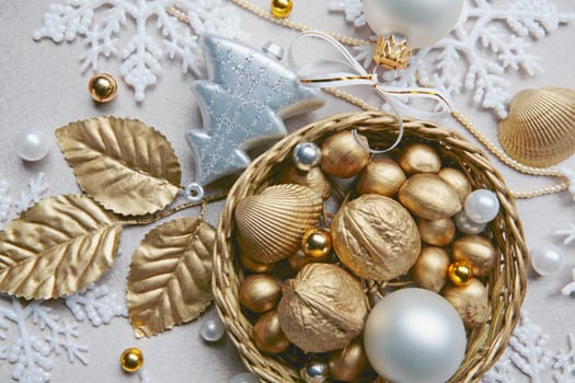 Golden nuts, shell, beads and white ball lying in the basket on the christmas backdrop