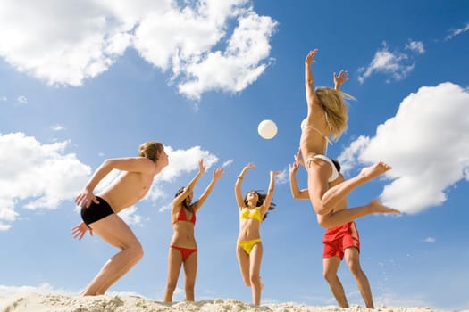 Photo of five friends playing with ball on sand