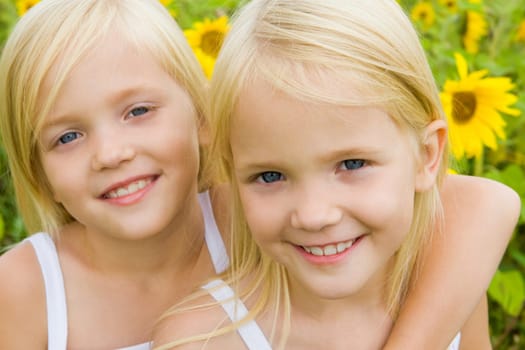 Portrait of cute girl embracing her twin sister and both looking at camera with smiles