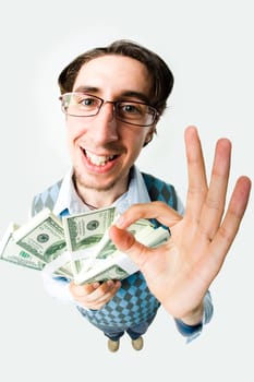Wide angle of young man with dollars showing sign of okay and looking at camera