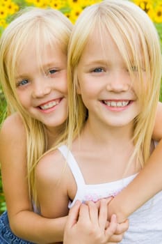 Portrait of cute girl embracing her twin sister and both looking at camera with smiles