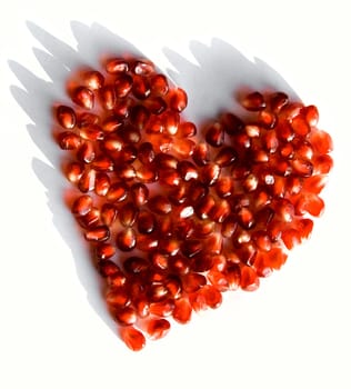 Creative photo of red heart made up of pomegranate seeds