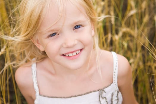 Image of youthful girl lying in wheat and looking at camera with smile