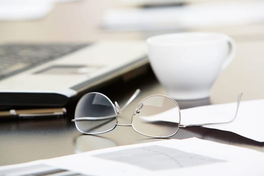 Close-up of papers, glasses and cup on workplace