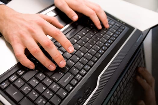 Close-up of male hand over black keyboard of laptop during typing