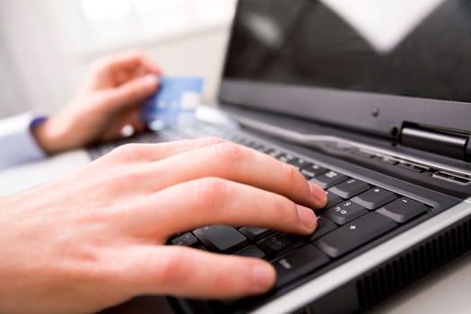 Close-up of male hand over black keyboard of laptop during typing
