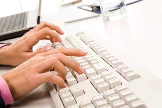 Close-up of female hand touching buttons of white computer keyboard