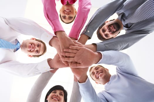 Below shot of smiling co-workers making pile of hands