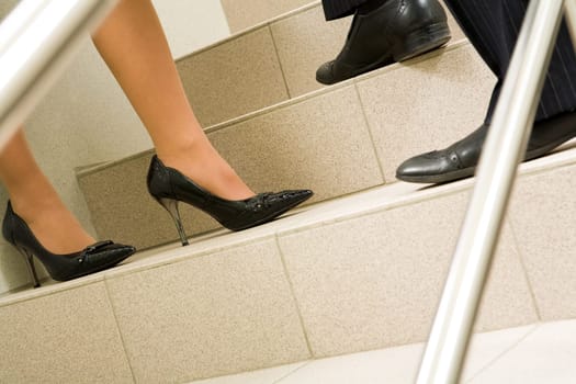 Image of female and male legs standing on marble ladder at meeting