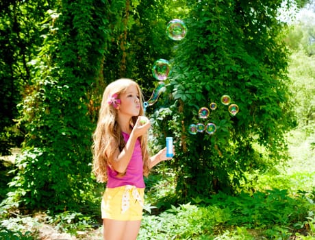 Children girl blowing soap bubbles in outdoor forest
