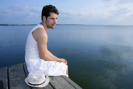 Mediterranean young latin man relaxed on wood pier white hat