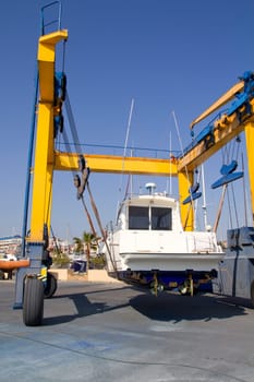 boat yellow travelift crane holding motorboat under blue sky