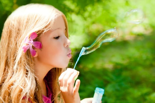 Children girl blowing soap bubbles in outdoor forest