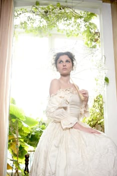 Victorian beautiful woman, white dress at home window with plants