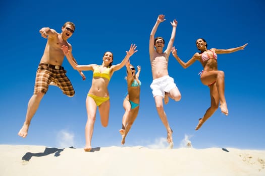Image of five energetic people jumping at the beach